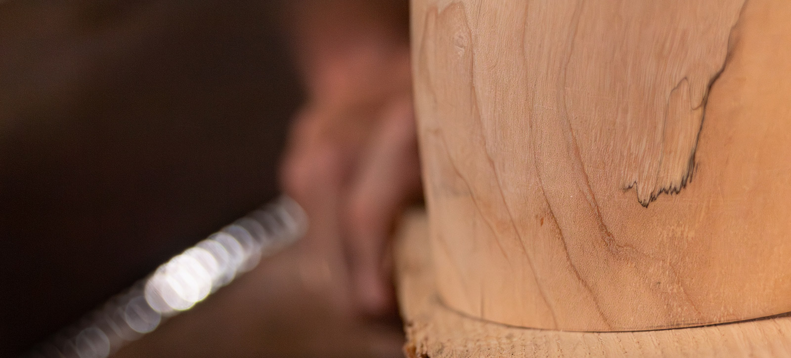 Tête de lampe artisanale Erebia Luminaires en train d'être conçue, gros plan sur le bois